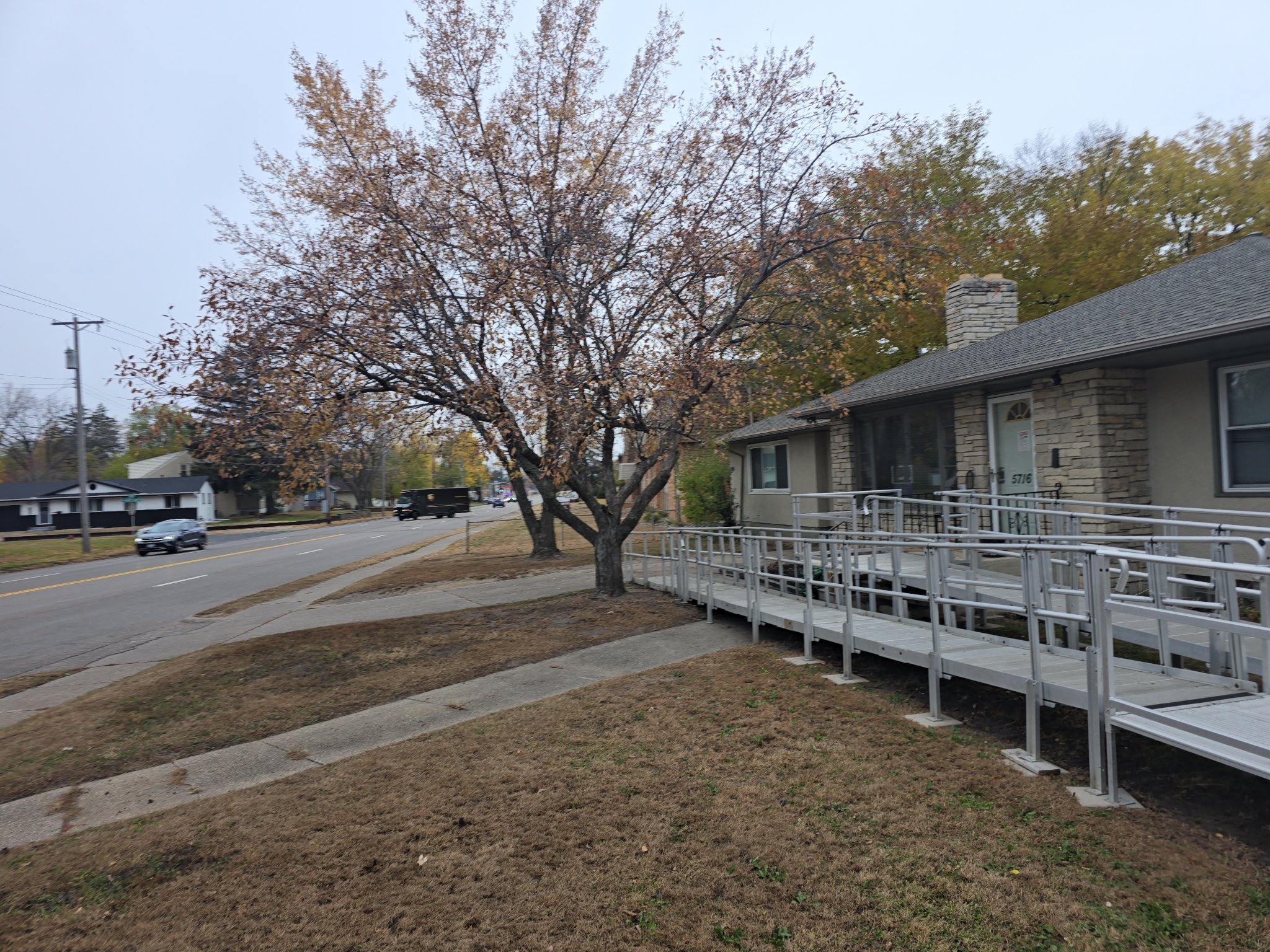 The same stone home after a fall cleanup, with a leaf-free yard and clean walkway